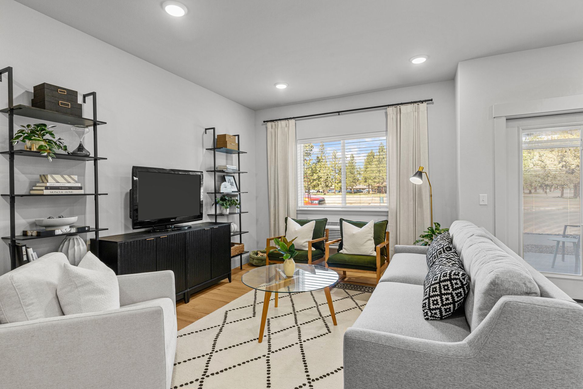 Living room with gray sofa, armchairs, and a black bookshelf.