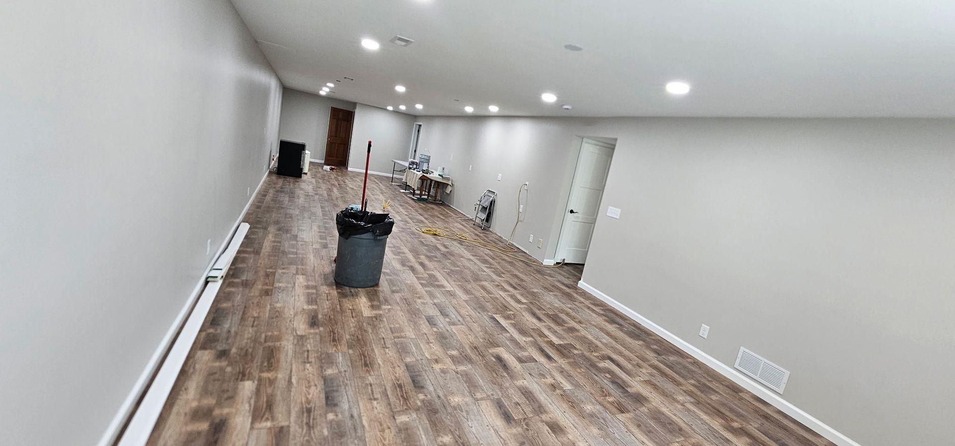 Interior of a room under construction with drywall installed. A person stands near a window on a scaffolding.