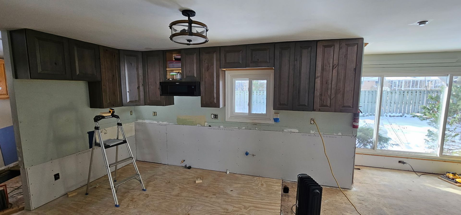 Wooden staircase leading upward, with a handrail on the left, set between two gray walls.