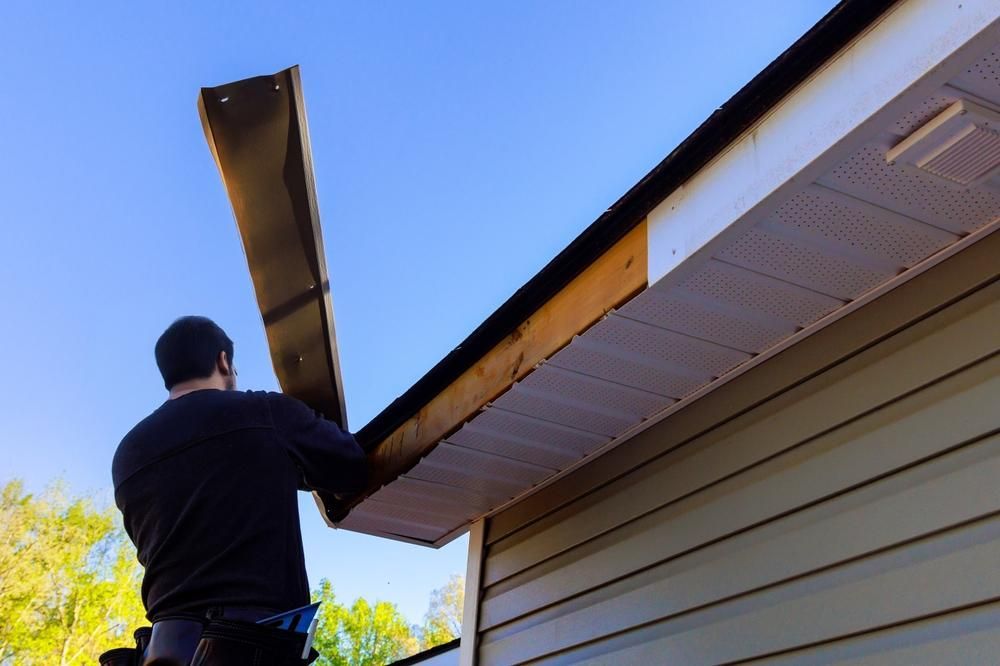 Person installing a soffit on a house exterior.