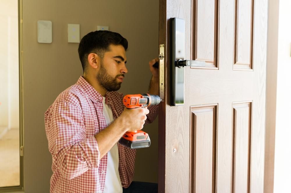 Man using a power drill to install a smart lock on a brown door.