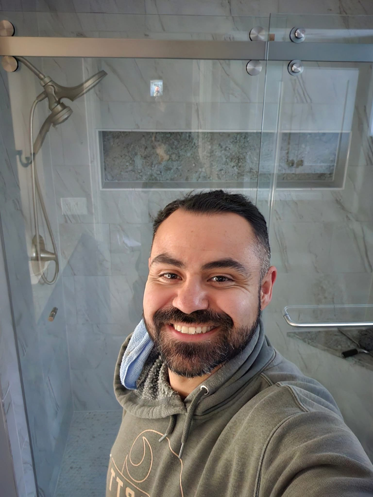 Person applying joint compound to drywall near a window, using a ladder in a room.