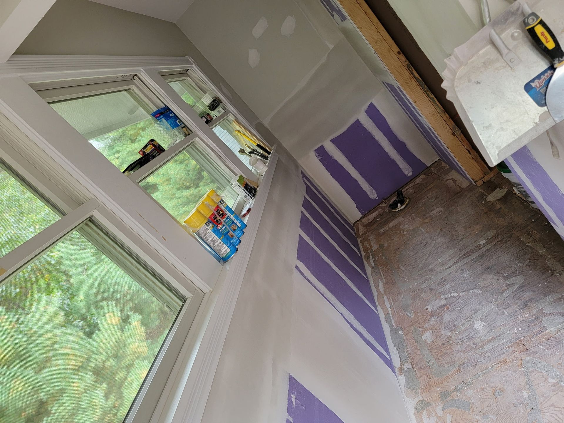 Interior construction: Drywall installed around window, unfinished, purple drywall visible.