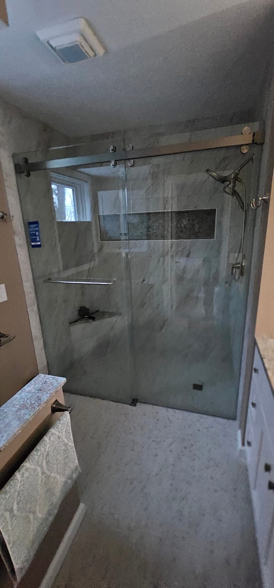 A modern shower with glass doors and a gray tiled interior.