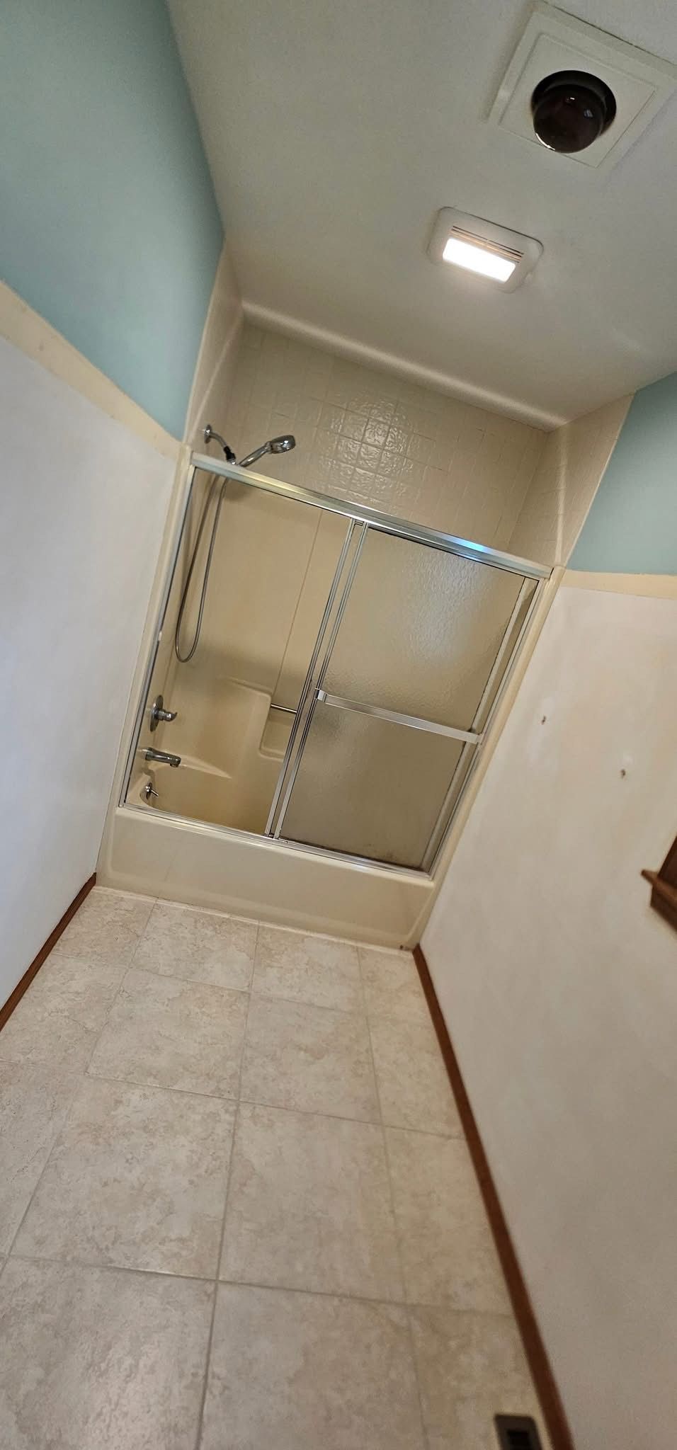 Bathroom with a shower stall, tile floor, and light blue walls.