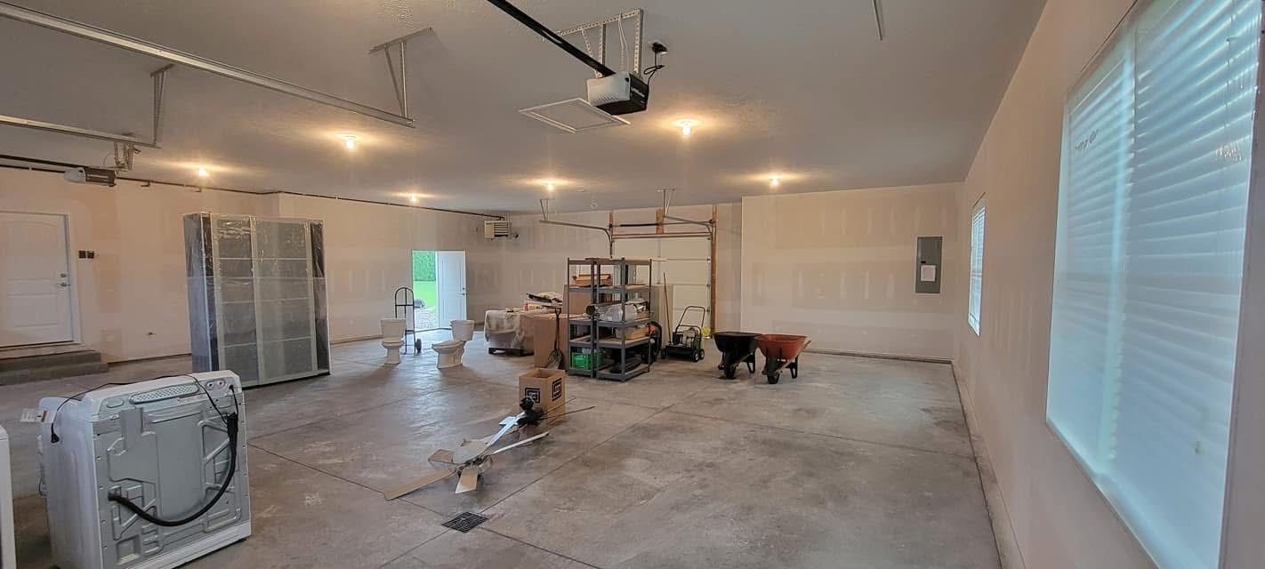 A wide, empty garage with boxes, a washer, and a garage door opener. The room has concrete floors.