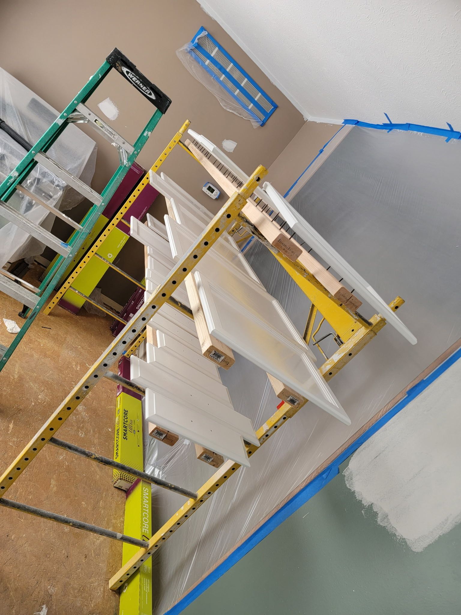 Ladder holding freshly painted trim in a room with partially painted walls.