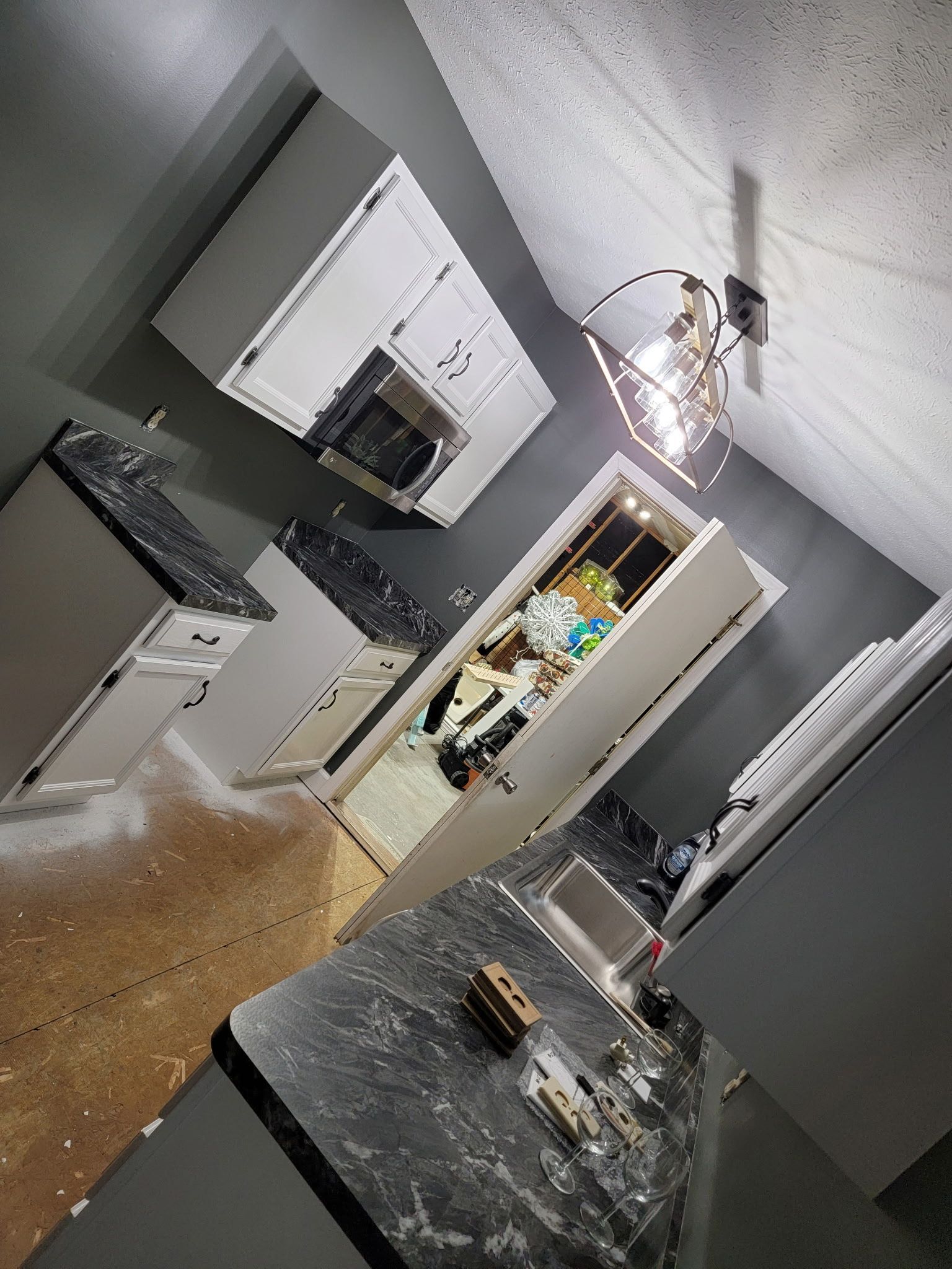 Kitchen with cabinets, countertop, and doorway filled with debris. Gray and white colors.