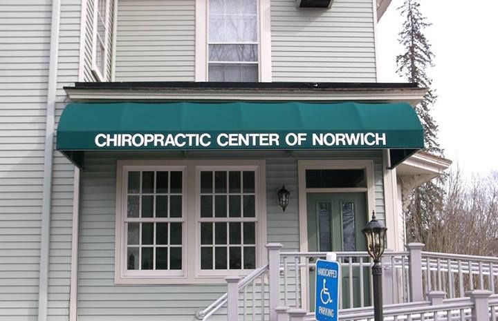 A building with a green awning that says chiropractic center of norwich