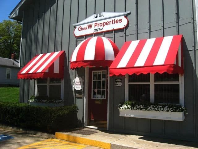 A gray building with red and white awnings and a sign that says gww properties