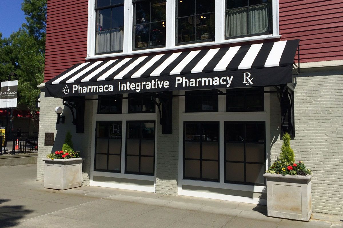 The front of a pharmacy with a black and white awning.
