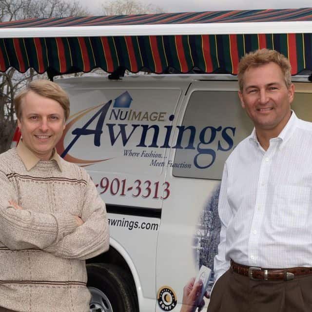 Two men standing in front of a nu image awnings van