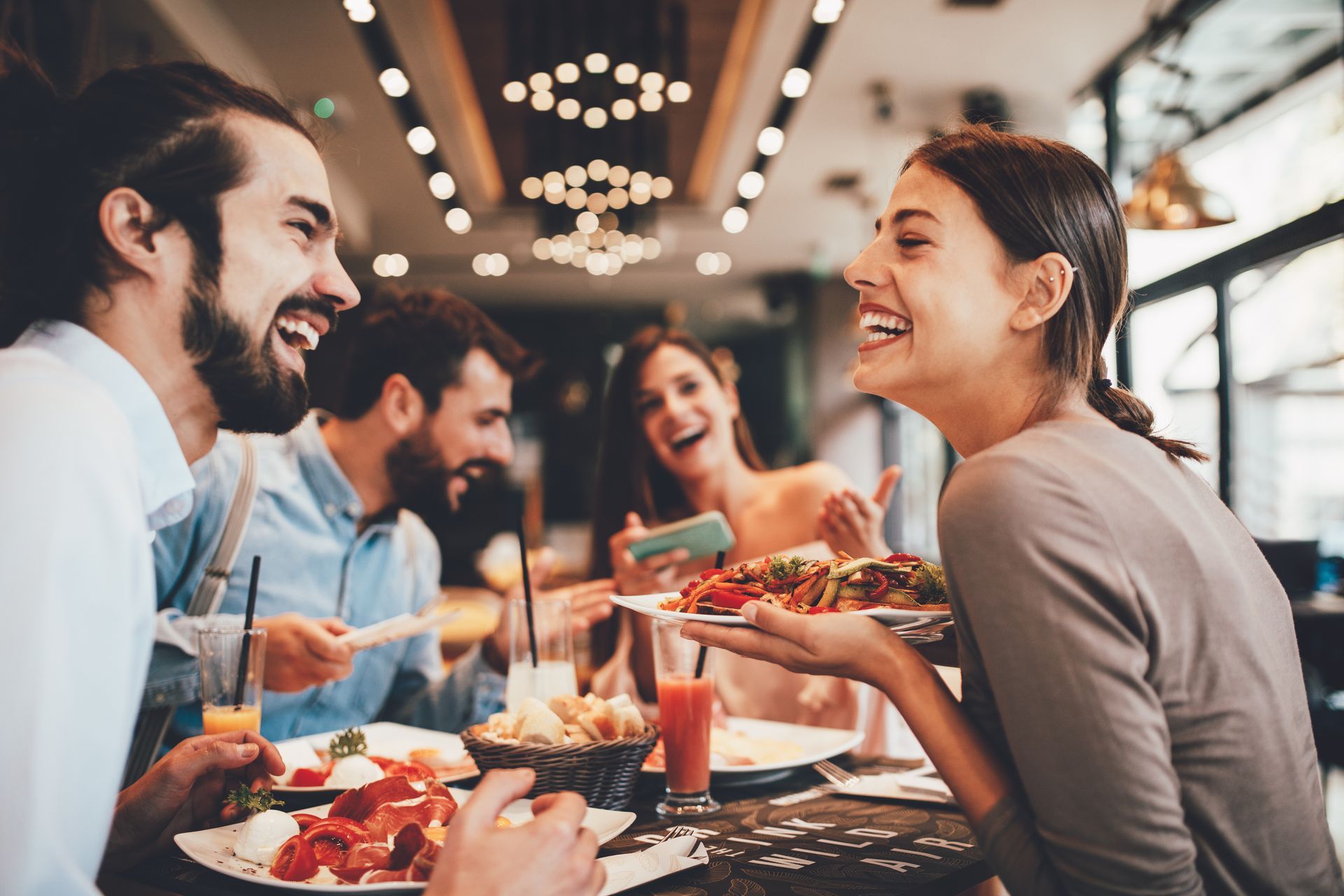 A group of people are sitting at a table in a restaurant eating food.