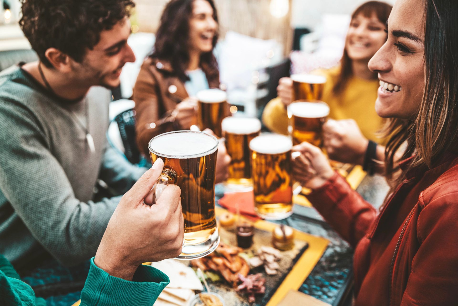 A group of people are sitting at a table toasting with beer.