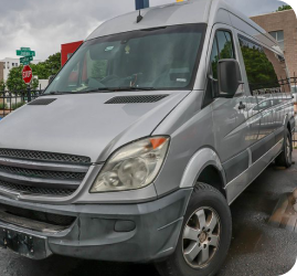 A silver Mercedes-Benz Sprinter van parked on a street near a stop sign | Firos Auto House 2