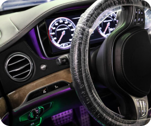 Luxury car interior featuring a steering wheel covered in protective plastic, a digital dashboard, and ambient lighting | Firos Auto House 2