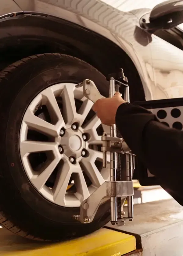 A mechanic attaches a wheel alignment sensor to the rim of a car tire in an auto repair shop.