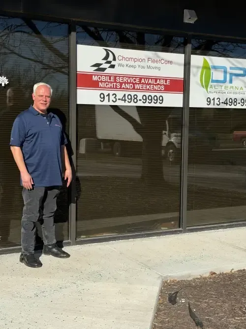 A person in a blue polo shirt stands outside a storefront displaying a business sign with the phone number 913-498-9999.