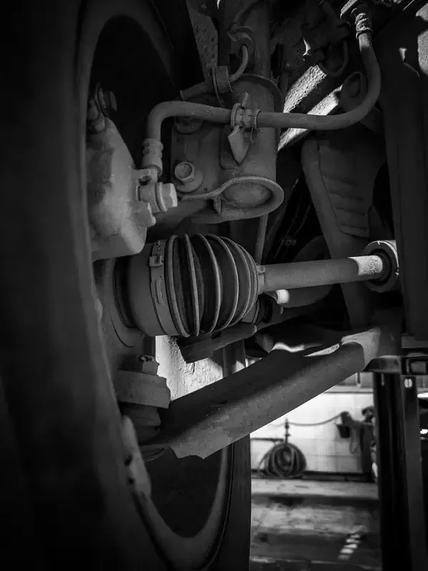 A low-angle view of a vehicle's undercarriage showing the wheel suspension, brake components, and a CV joint axle.