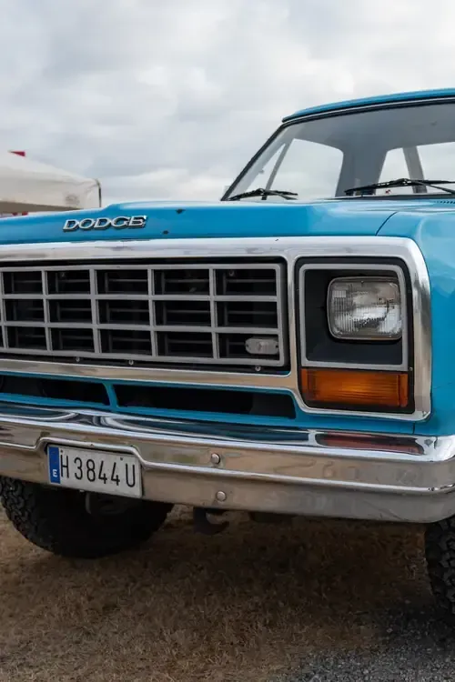 A bright blue vintage Dodge pickup truck front, featuring a chrome grille, square headlights, and a license plate.