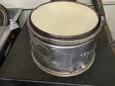 A circular, metallic industrial catalytic converter filter sits on a dark surface, showing a honeycomb ceramic core.