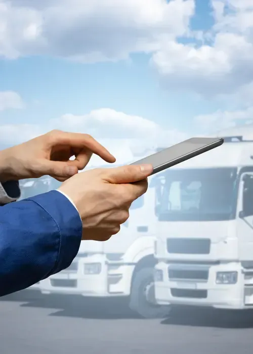 Hands holding a tablet displaying a fleet management dashboard with charts against a background of parked yellow vans.