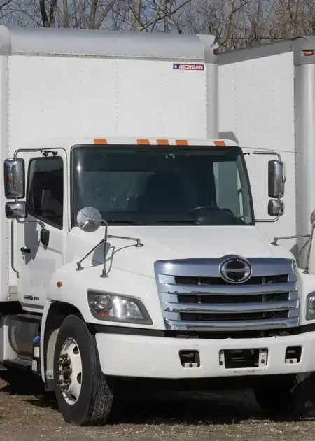 A white Hino fuel tanker truck stopped on a city street, displaying a yellow 