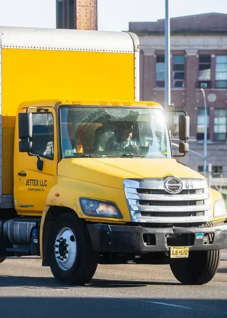 A white Hino light-duty commercial truck parked indoors on a blue floor mat.