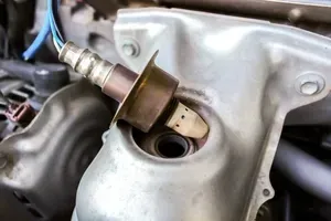 An automotive oxygen sensor is removed from its housing on an engine manifold.