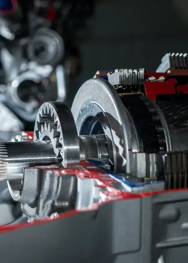 A close-up, cutaway view showing the internal metal gears, shafts, and components of an automotive transmission.