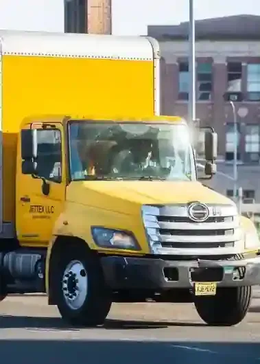 A white Hino light-duty commercial truck parked indoors on a blue floor mat.