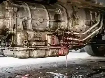 A vehicle transmission leaking bright red fluid from the connections to the metal cooling lines.