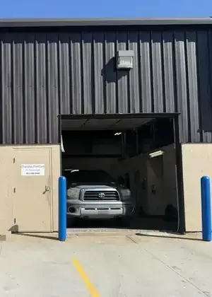 Front-facing view of a white Freightliner cab-over semi-truck parked inside a garage.
