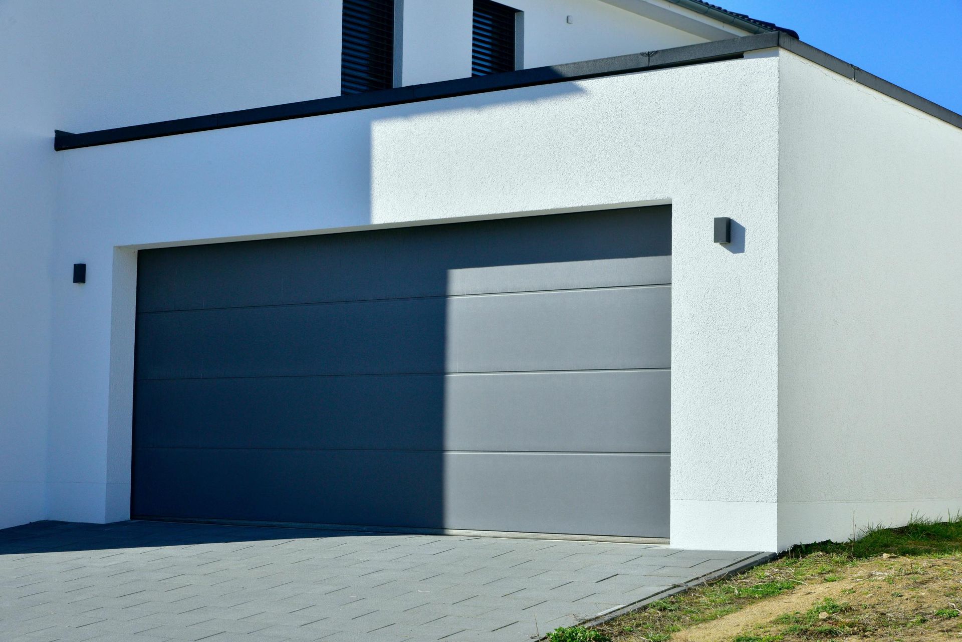 Modern white house with gray garage door. Driveway.