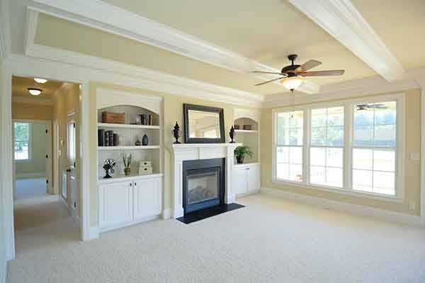 A living room with a fireplace and a ceiling fan.