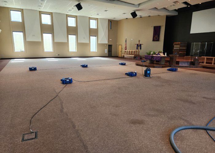 A large room with a lot of windows and a vacuum cleaner on the floor.