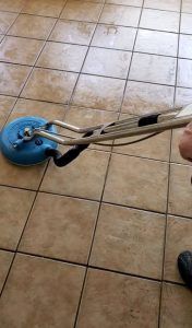 A person is cleaning a tile floor with a machine.
