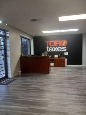 A large room with a wooden floor and a sign on the wall that says top taxes.