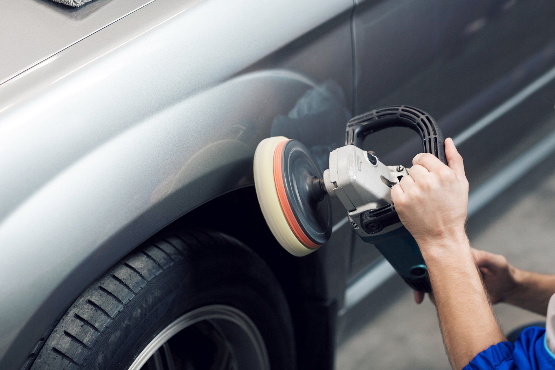 Close-up of hands worker using polisher to polish a car body in the workshop