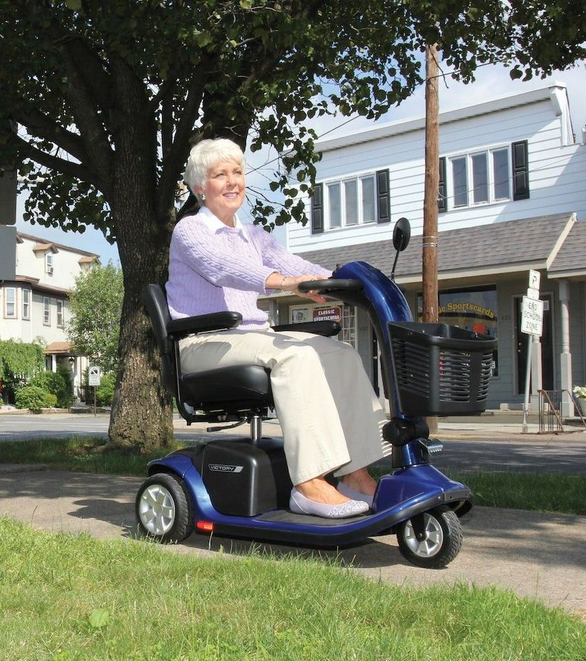 A man in a wheelchair is walking down a path in a park.