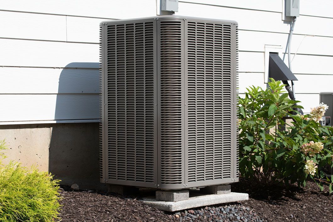 A large air conditioner is sitting outside of a house.