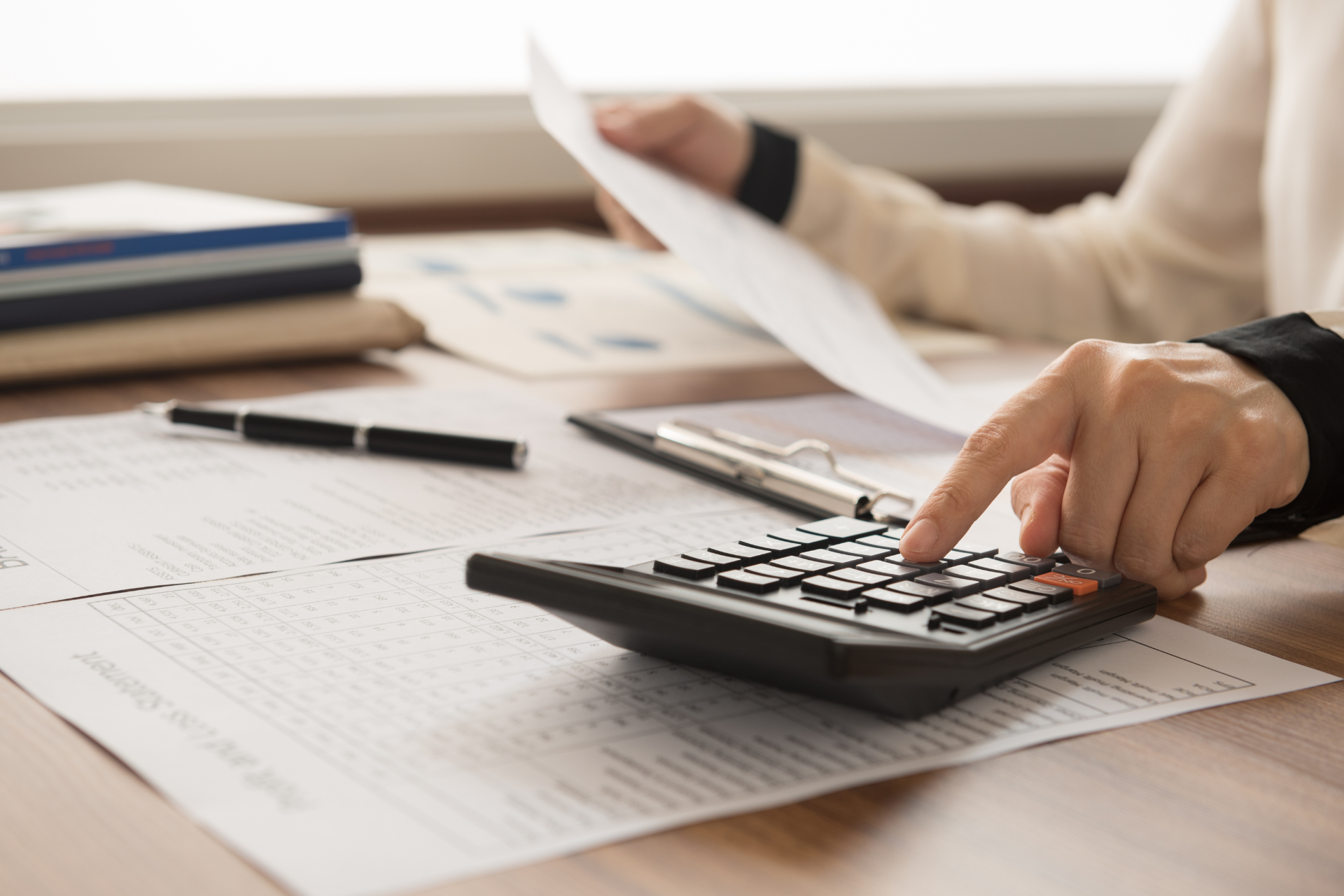 A person is using a calculator while holding a piece of paper.