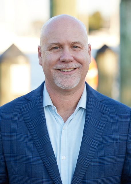 A bald man in a blue suit and white shirt is smiling for the camera.