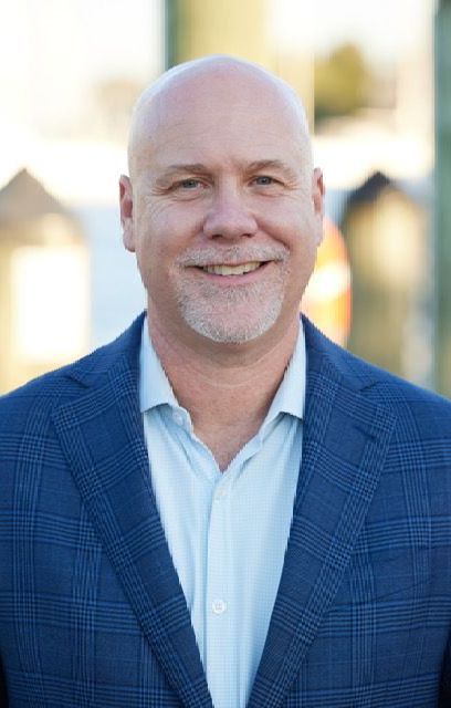 A bald man in a blue suit and white shirt is smiling for the camera.
