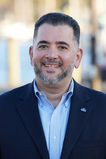 A man with a beard is wearing a suit and smiling for the camera.