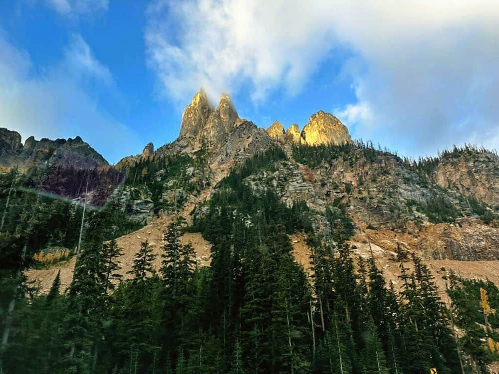 a mountain covered in trees with a blue sky in the background