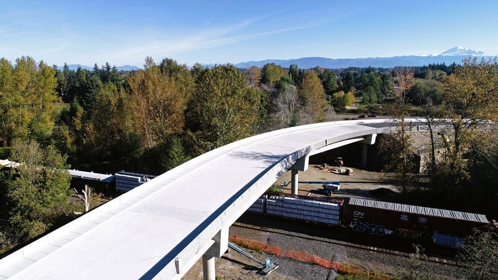 an aerial view of a bridge over a train track surrounded by trees .