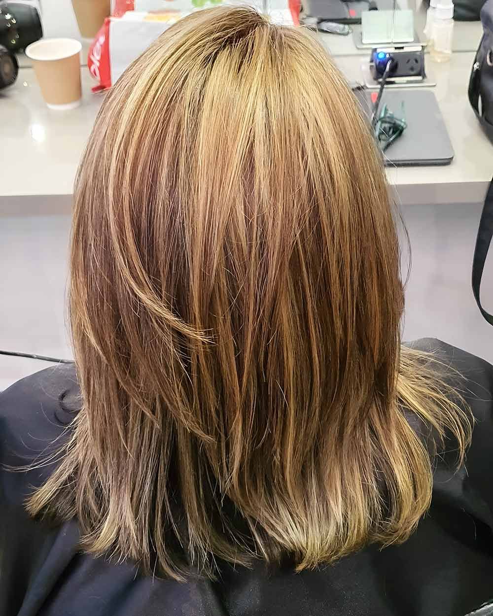 A Woman is Sitting in a Chair With Her Hair in a Ponytail — Artistry of Hair in Redlynch, QLD