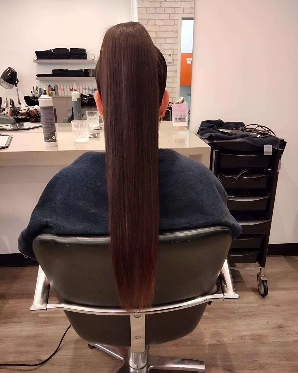A Woman With Very Long Hair is Sitting in a Chair — Artistry of Hair in Redlynch, QLD
