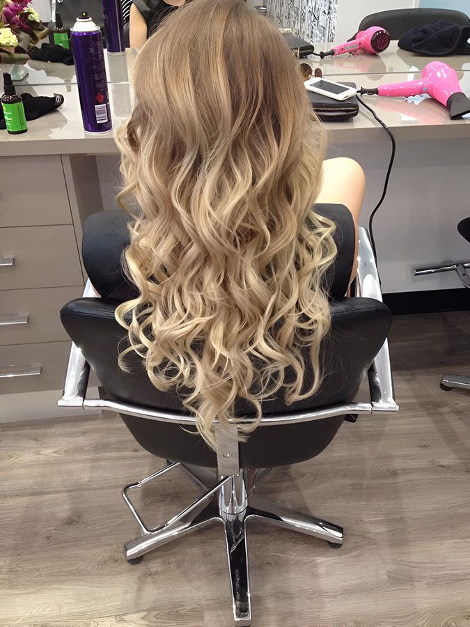 A Woman is Sitting in a Chair With Her Hair Blow Dried in a Salon — Artistry of Hair in Redlynch, QLD
